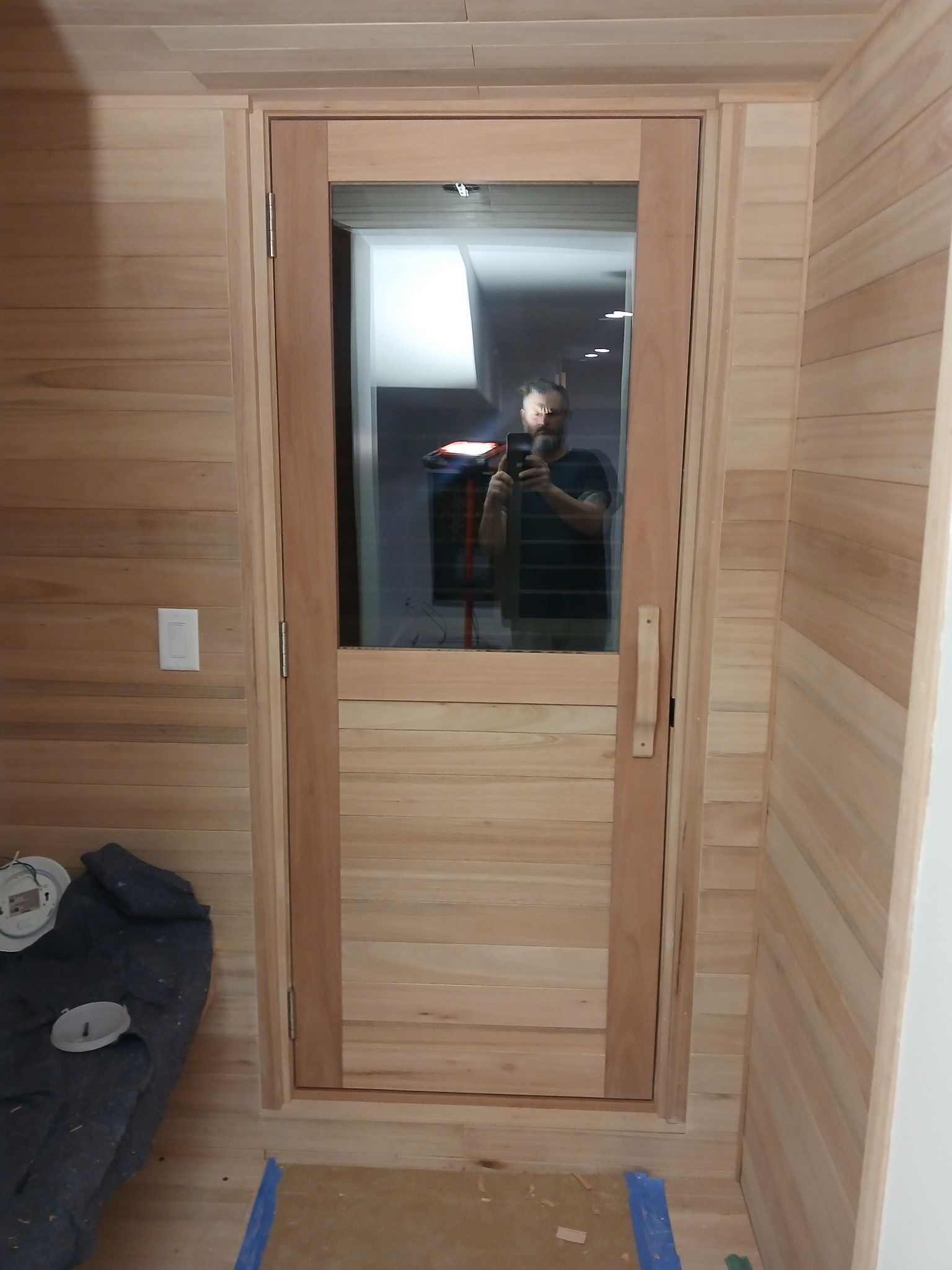 A person is taking a picture of themselves in a wooden door.