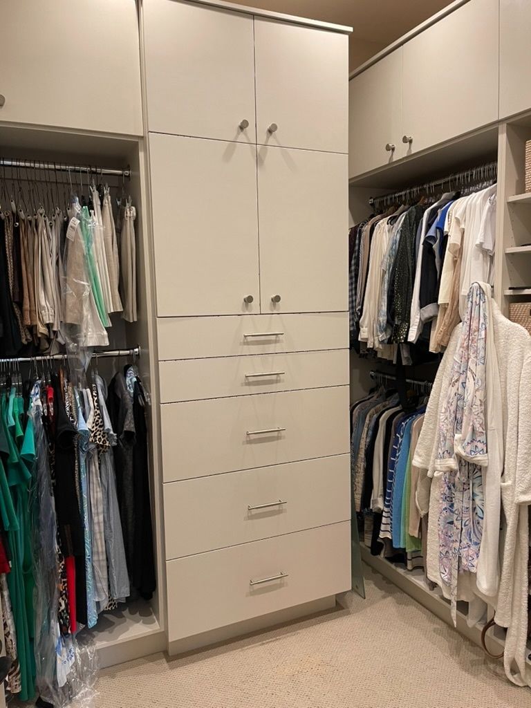 A walk in closet filled with lots of clothes and drawers.