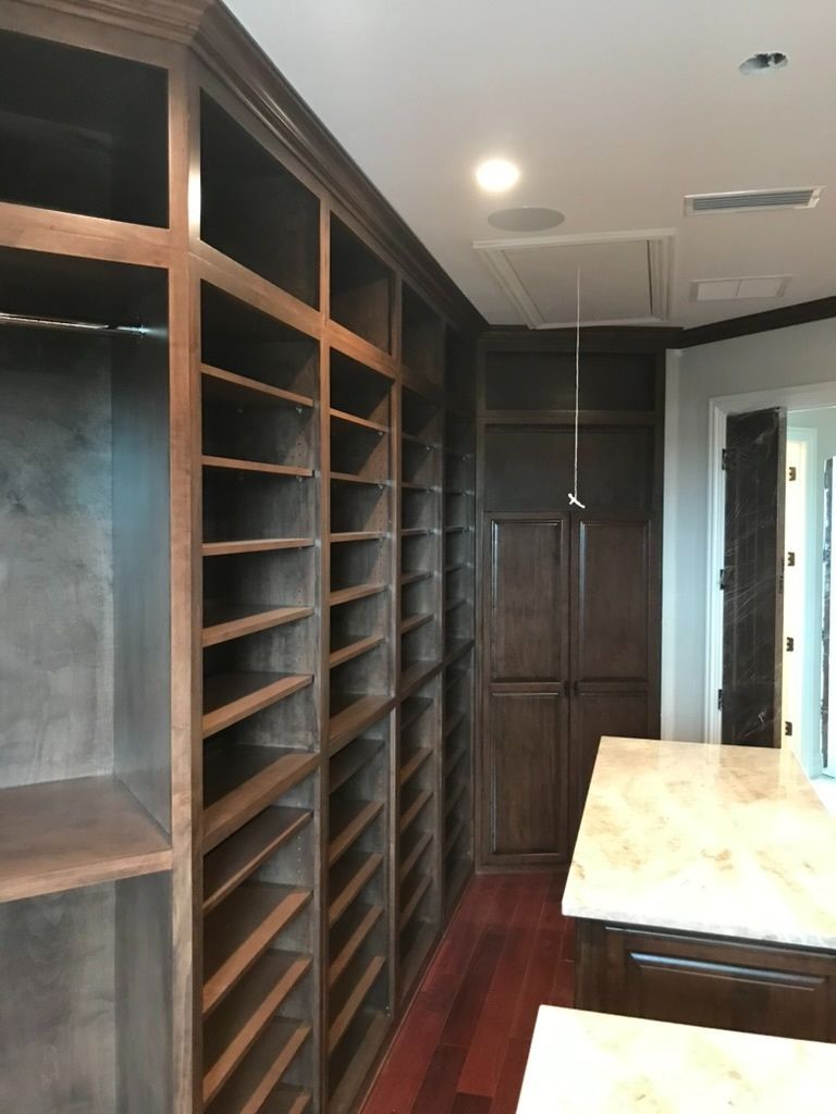 A walk in closet with lots of shelves and a marble counter top.