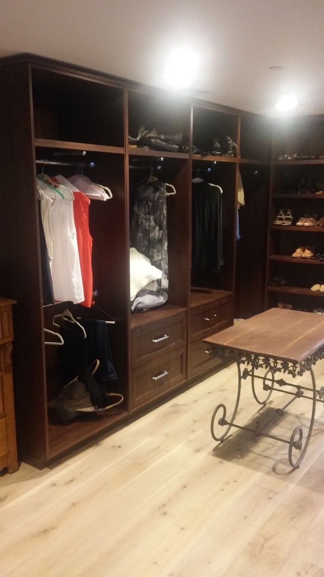A walk in closet with lots of clothes and a table.