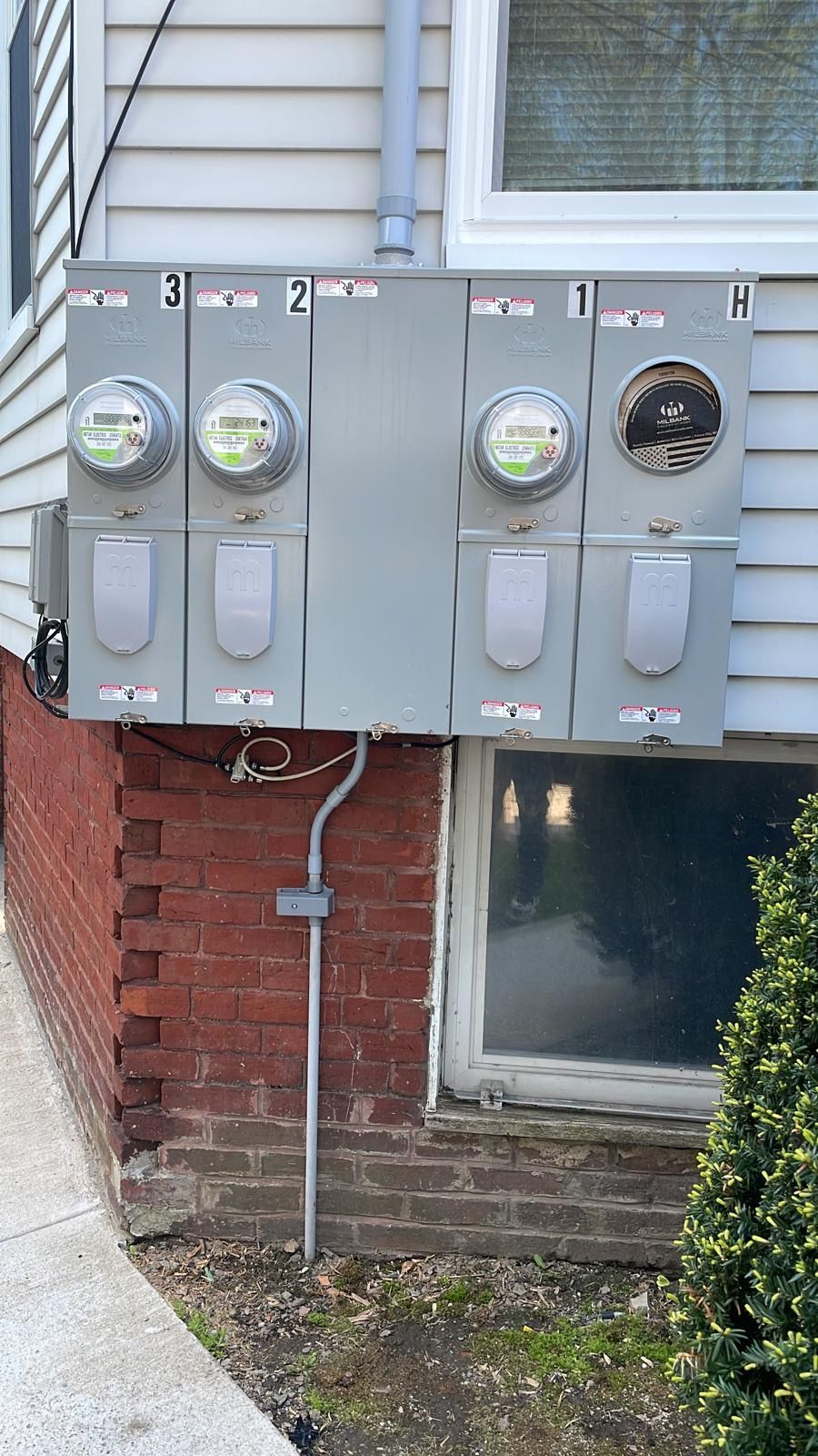 A row of four electrical meters mounted on the side of a building, with one meter missing from the far right housing.