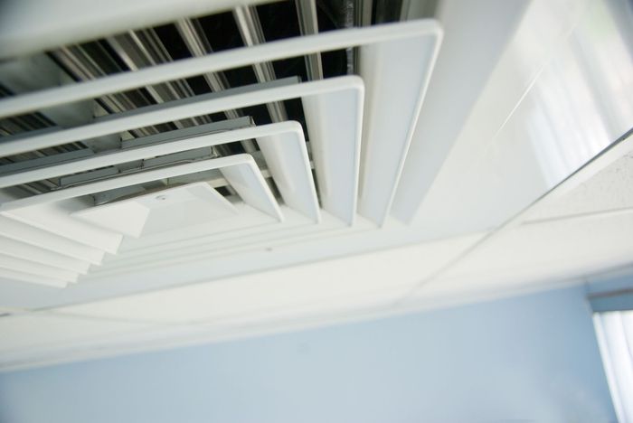 A close up of a white air vent on the ceiling of a room.