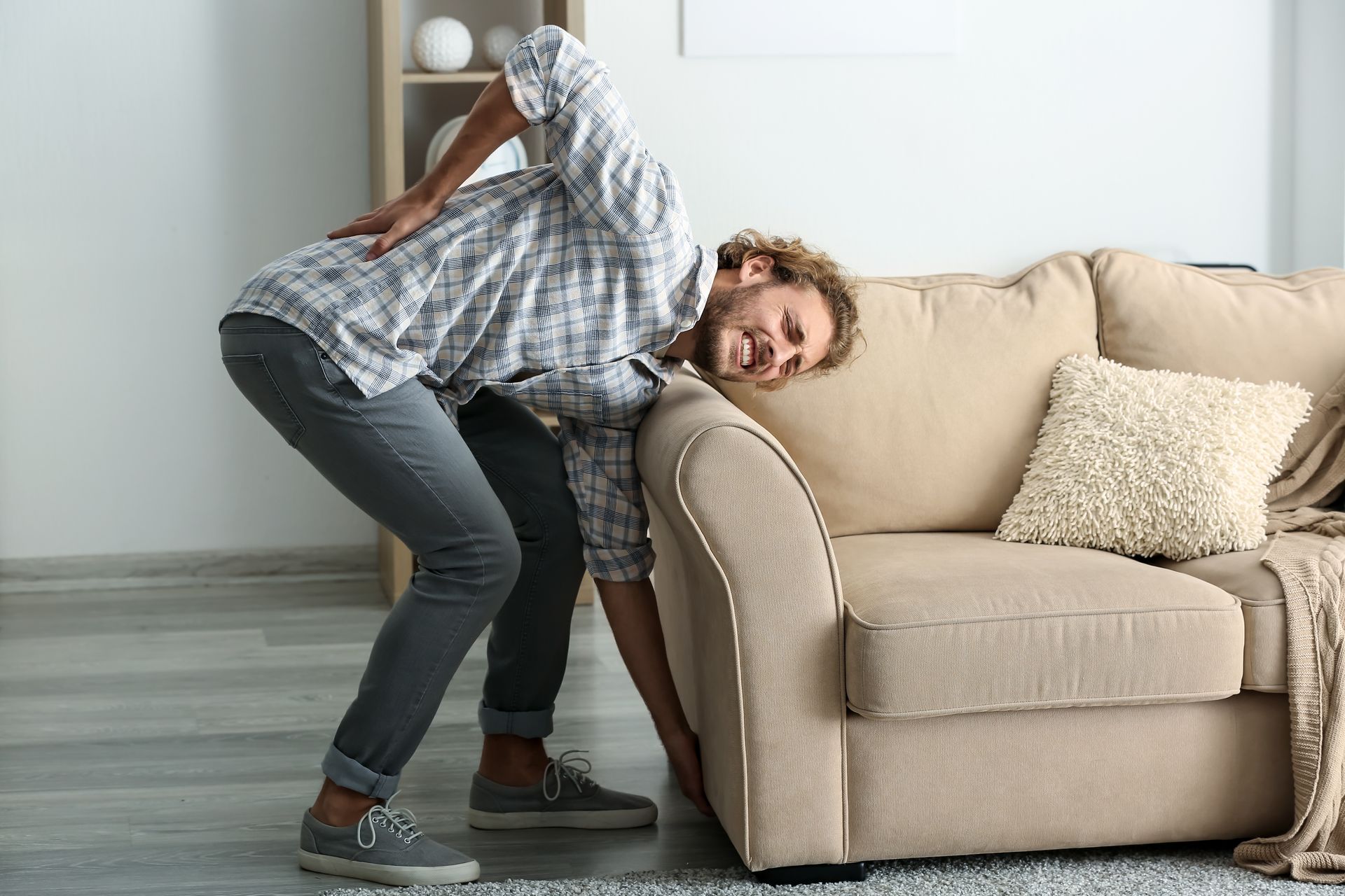 Young man suffering from back pain after carrying heavy furniture