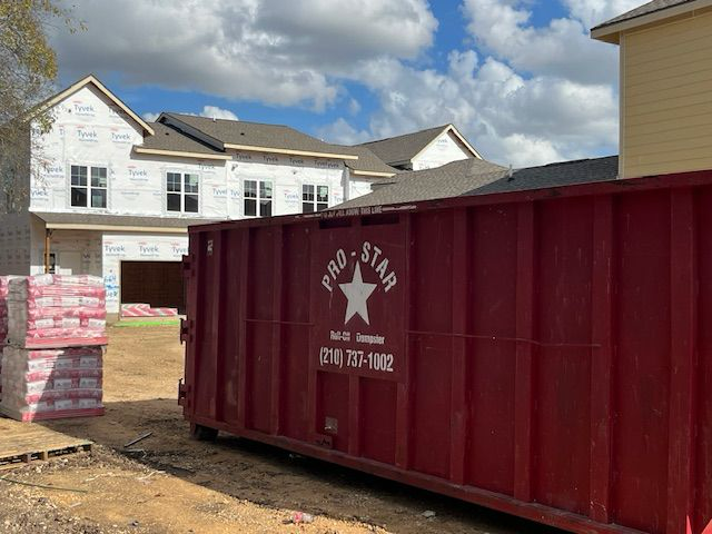 Close-up of a red dumpster filled with furniture and other items set against a clear blue sky