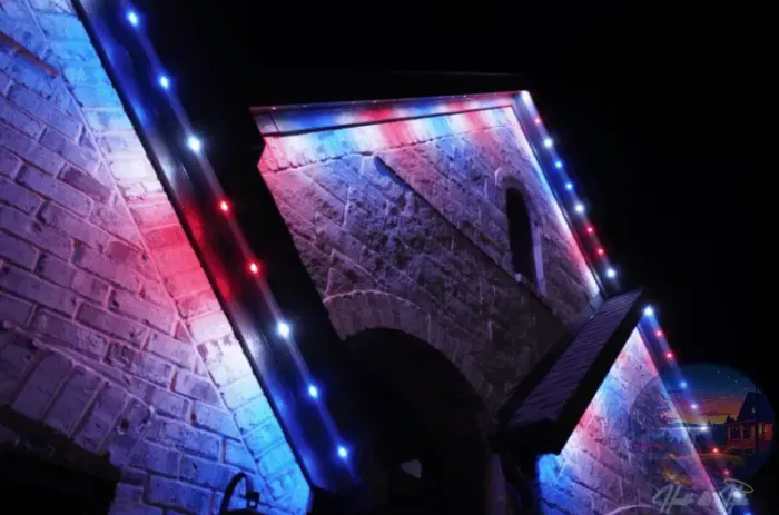 Stone house illuminated at night, blue sky, outdoor lighting.