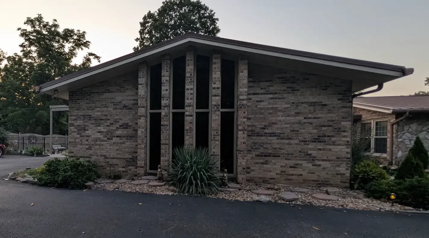 A single-story brick building with a slanted roof and tall, vertical windows.