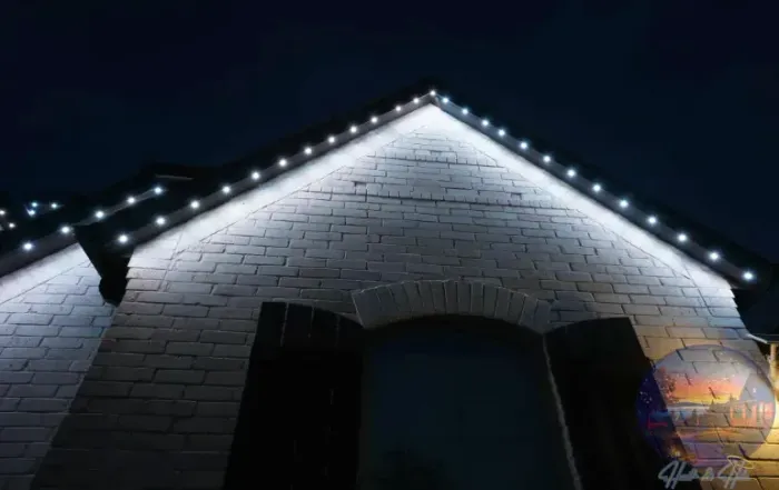 Brick building with white lights outlining the roof at night.