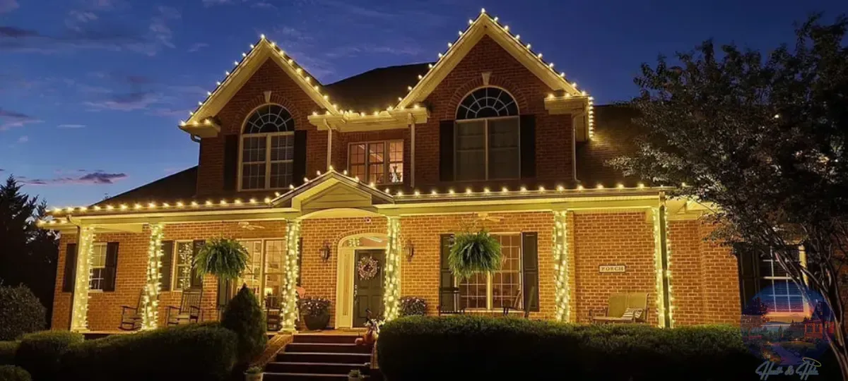 A brick house decorated with Christmas lights at dusk.