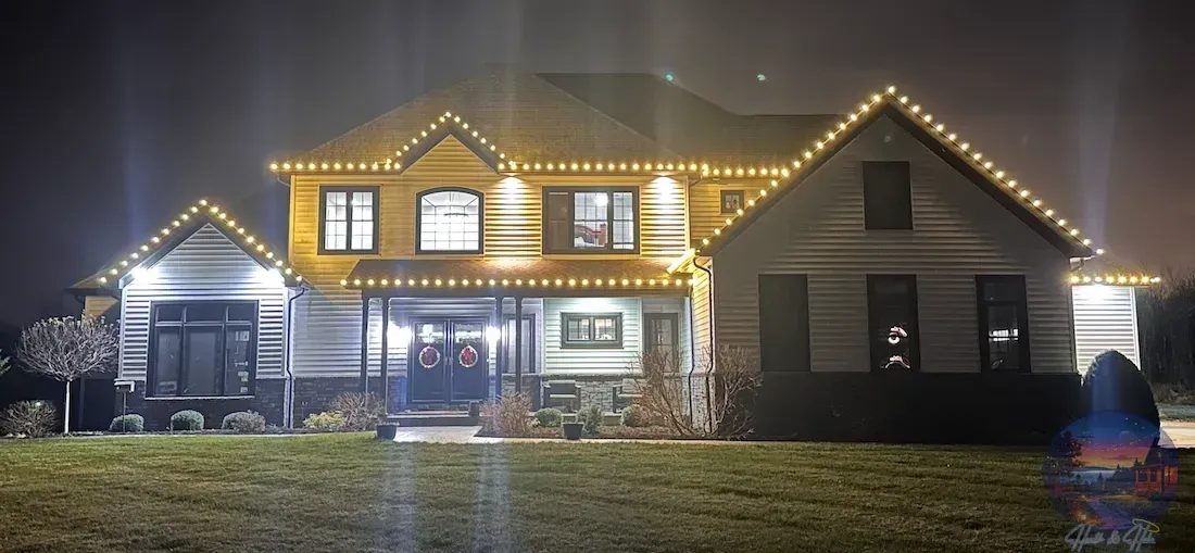 House at night lit with string lights along the roof line.