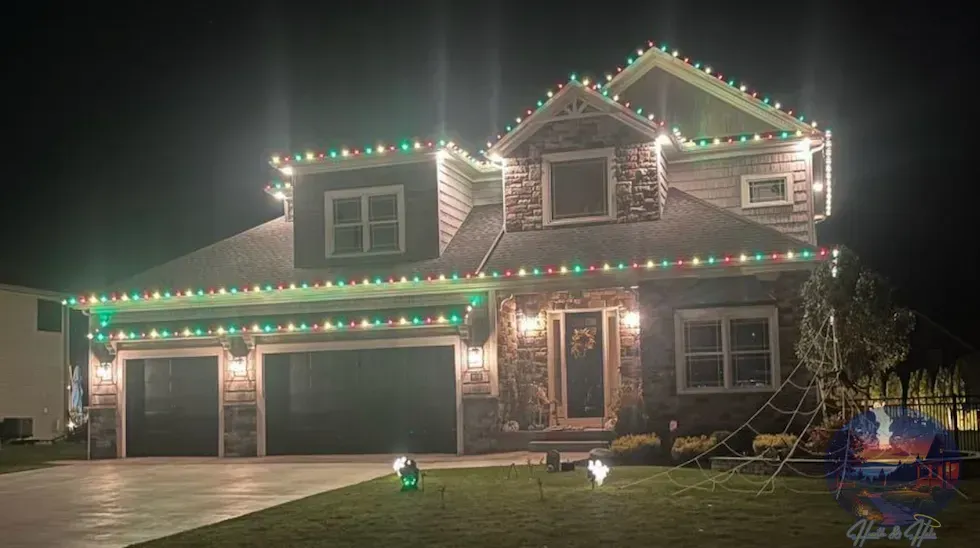 House exterior decorated with red and green Christmas lights at night.