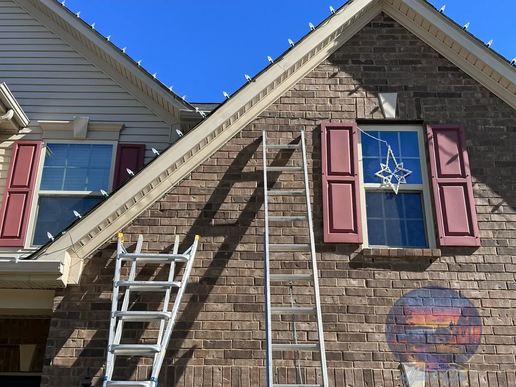 House decorated with landscape lighting, Christmas lights, covered in snow, at night.