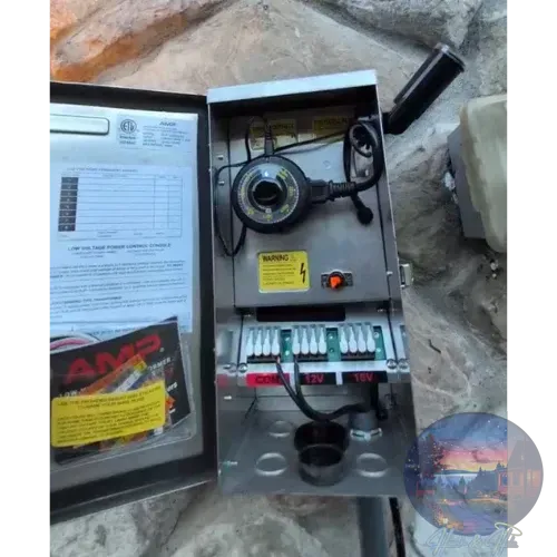 Open outdoor electrical box with timer and wiring for landscape lighting.