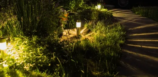 Lit garden path at night with solar lights illuminating grass and a walkway.