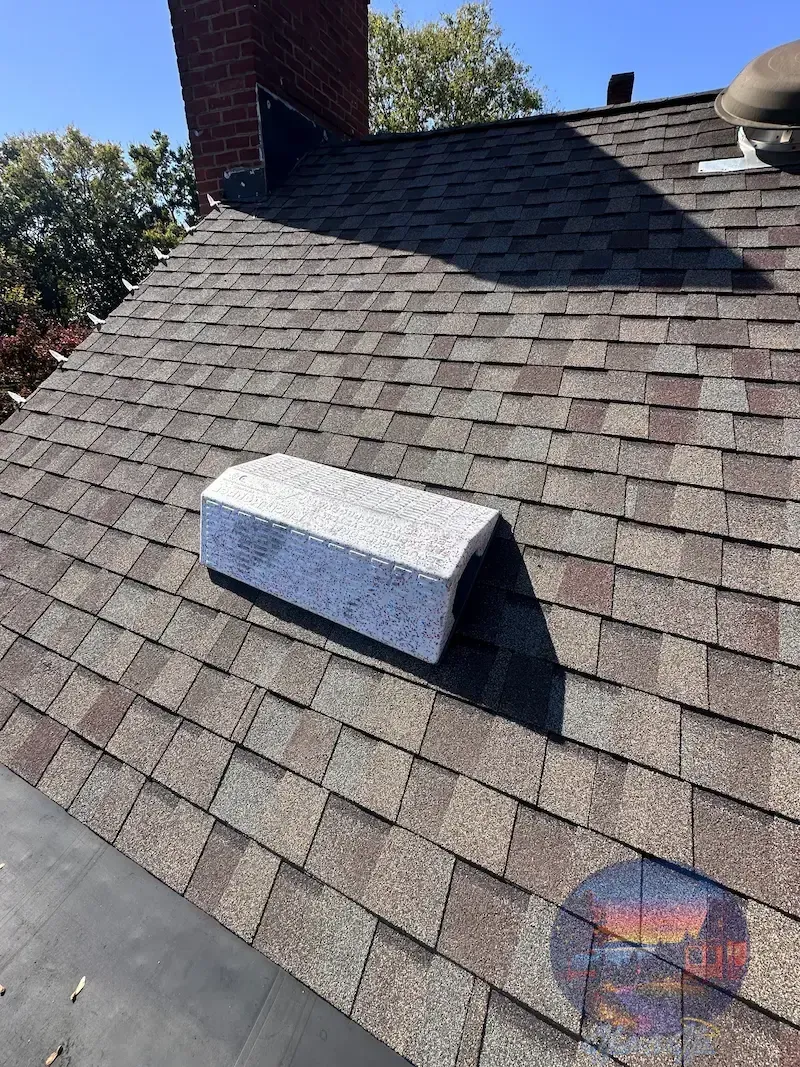 Asphalt shingle roof with a pitch hopper, brick chimney, and blue sky.