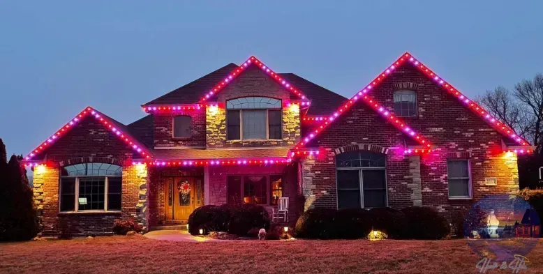 House decorated with pink and red Christmas lights against a twilight sky.