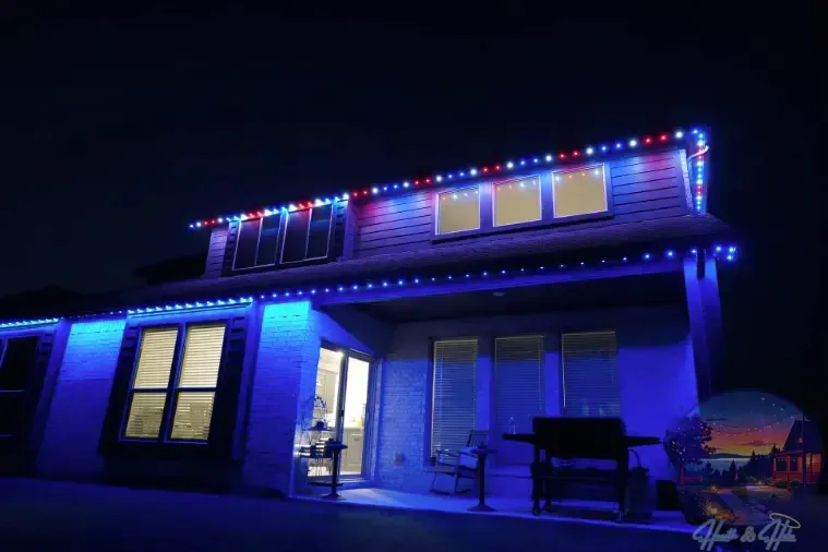 A two-story house at night illuminated with red and blue Christmas lights.