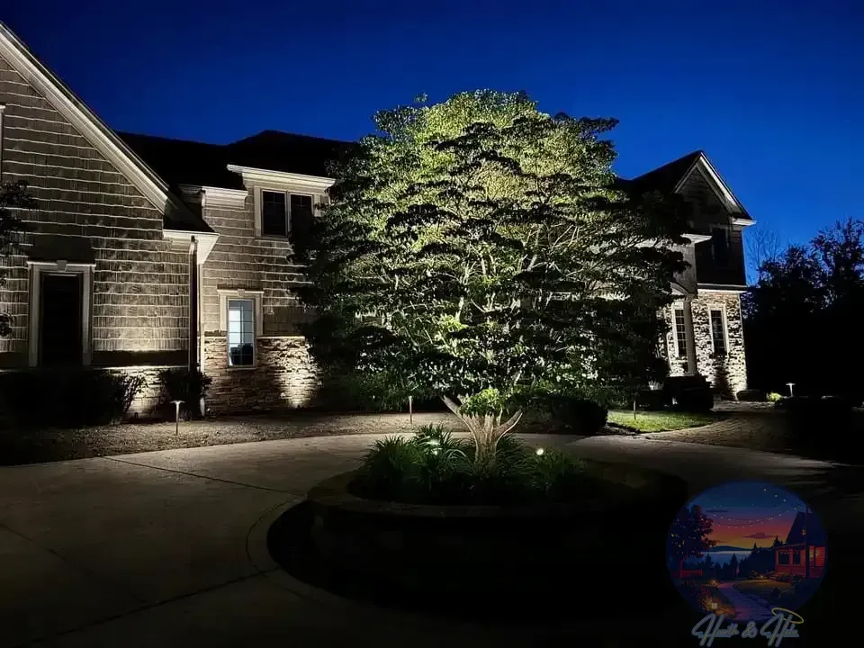 Lit pathway with recessed lights in stone leading towards a garden and lawn, illuminated by more lights.