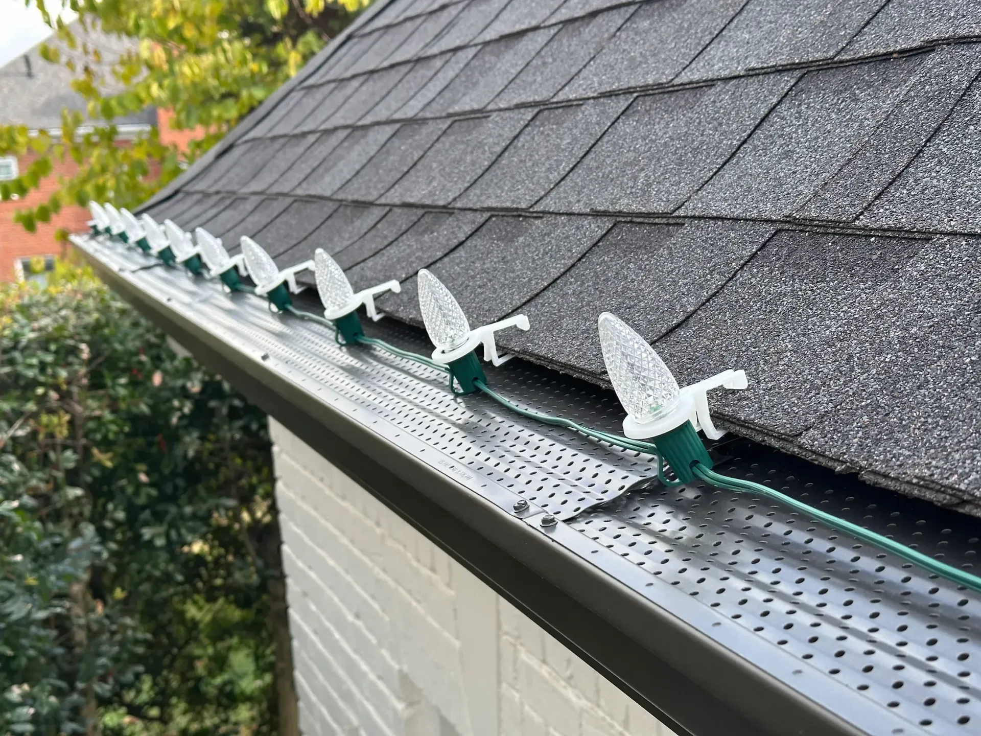Christmas lights clipped to a gutter on a house roof.