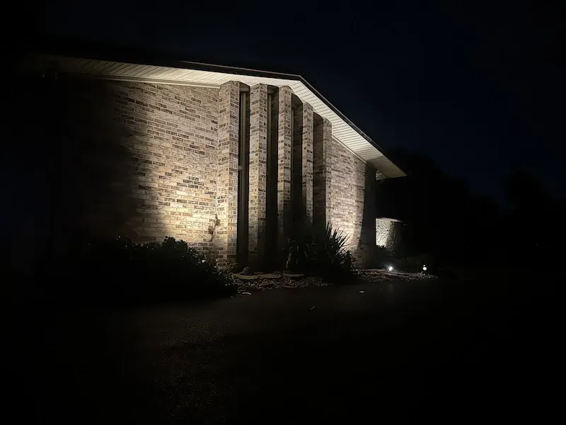 Brick building illuminated at night with spotlights, showcasing architectural details.