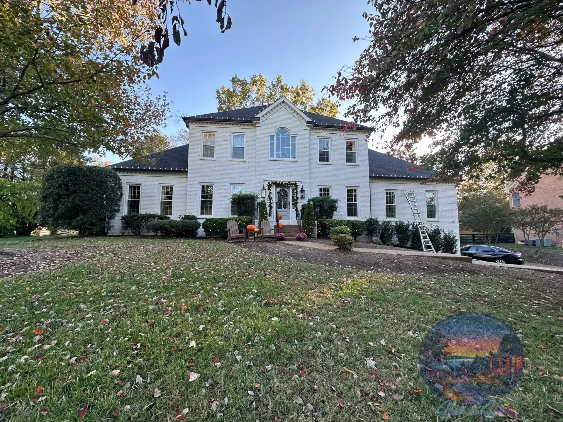 White two-story house with green lawn and fall foliage.