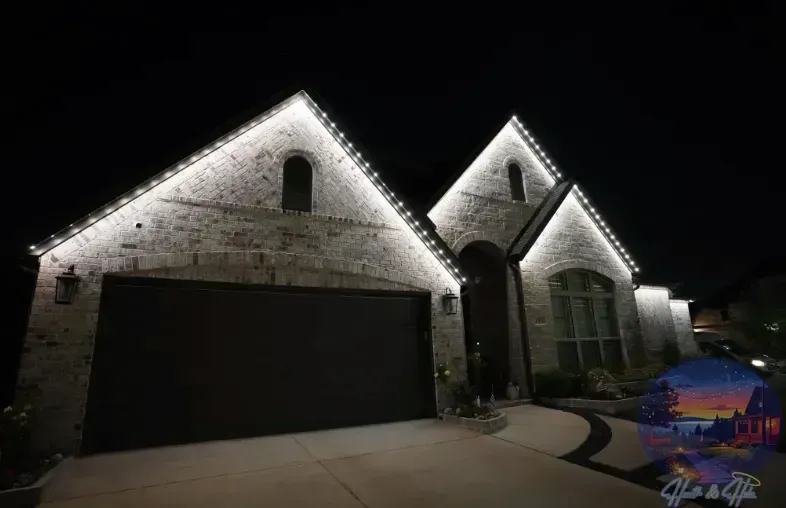 A house with white lights outlining the roof at night. Brick exterior, black garage door, and a curved driveway.