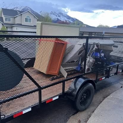A trailer filled with junk is parked on the side of the road.
