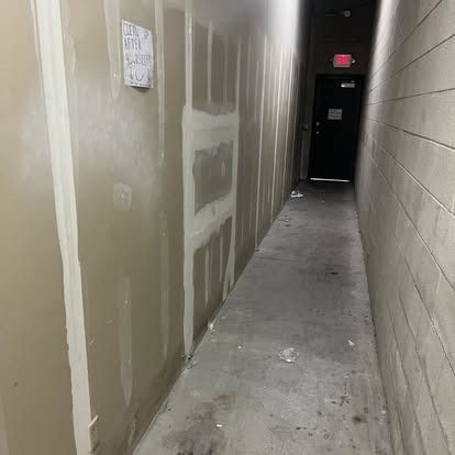 A long hallway with brick walls and a door.