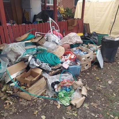 A pile of trash is sitting on the ground in front of a house.