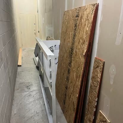 A hallway with a stack of plywood on the floor.