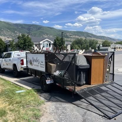 A truck with a trailer full of junk is parked on the side of the road.
