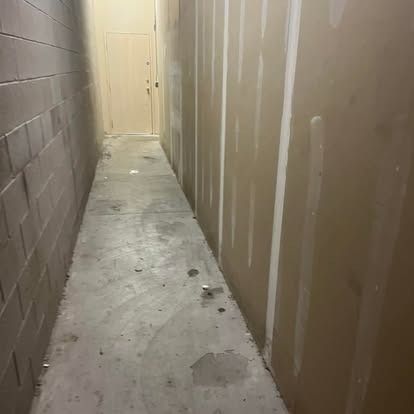 A long hallway with brick walls and a concrete floor.