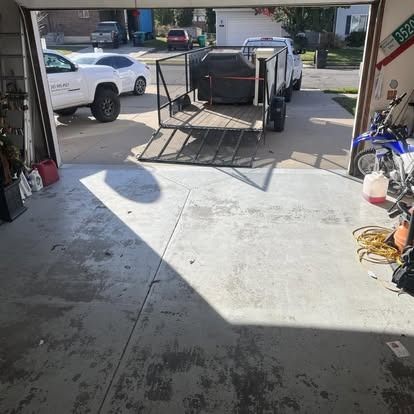 A trailer is parked in a garage next to a motorcycle.