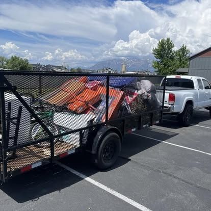 A truck is towing a trailer full of junk in a parking lot.