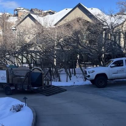 A white truck is parked in front of a snowy house.