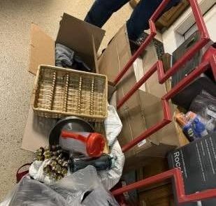 A person is standing next to a pile of boxes and baskets.