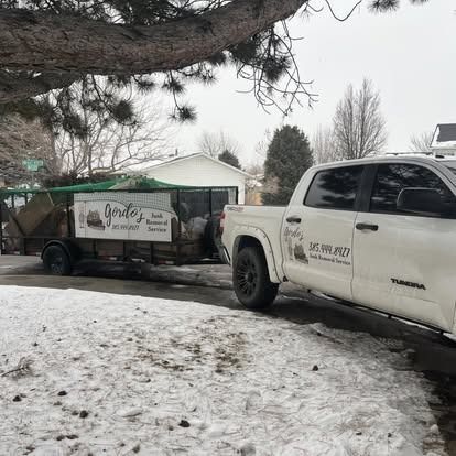 A white truck is parked next to a trailer in the snow.
