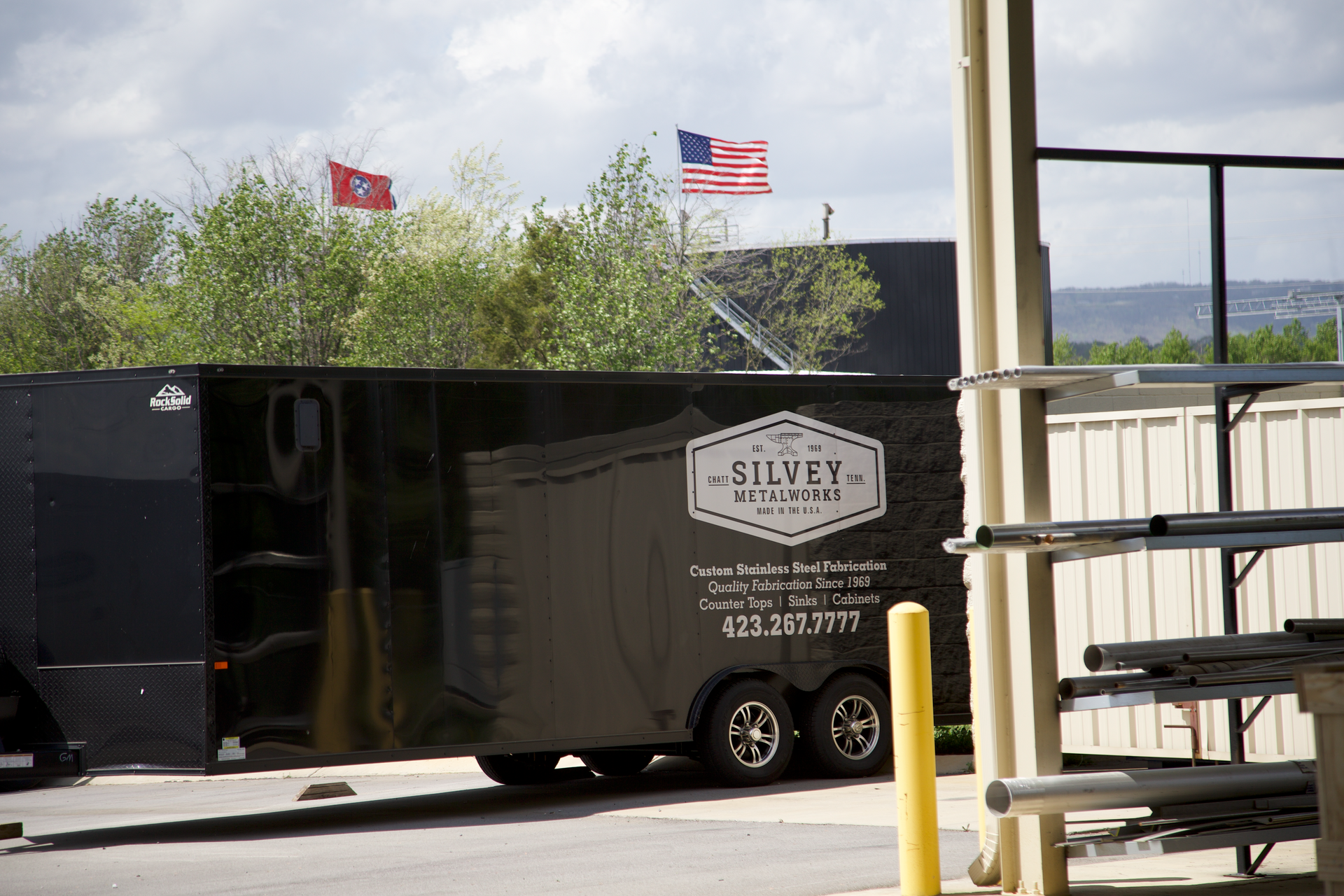 A black trailer with the word silver on it is parked in front of a building.