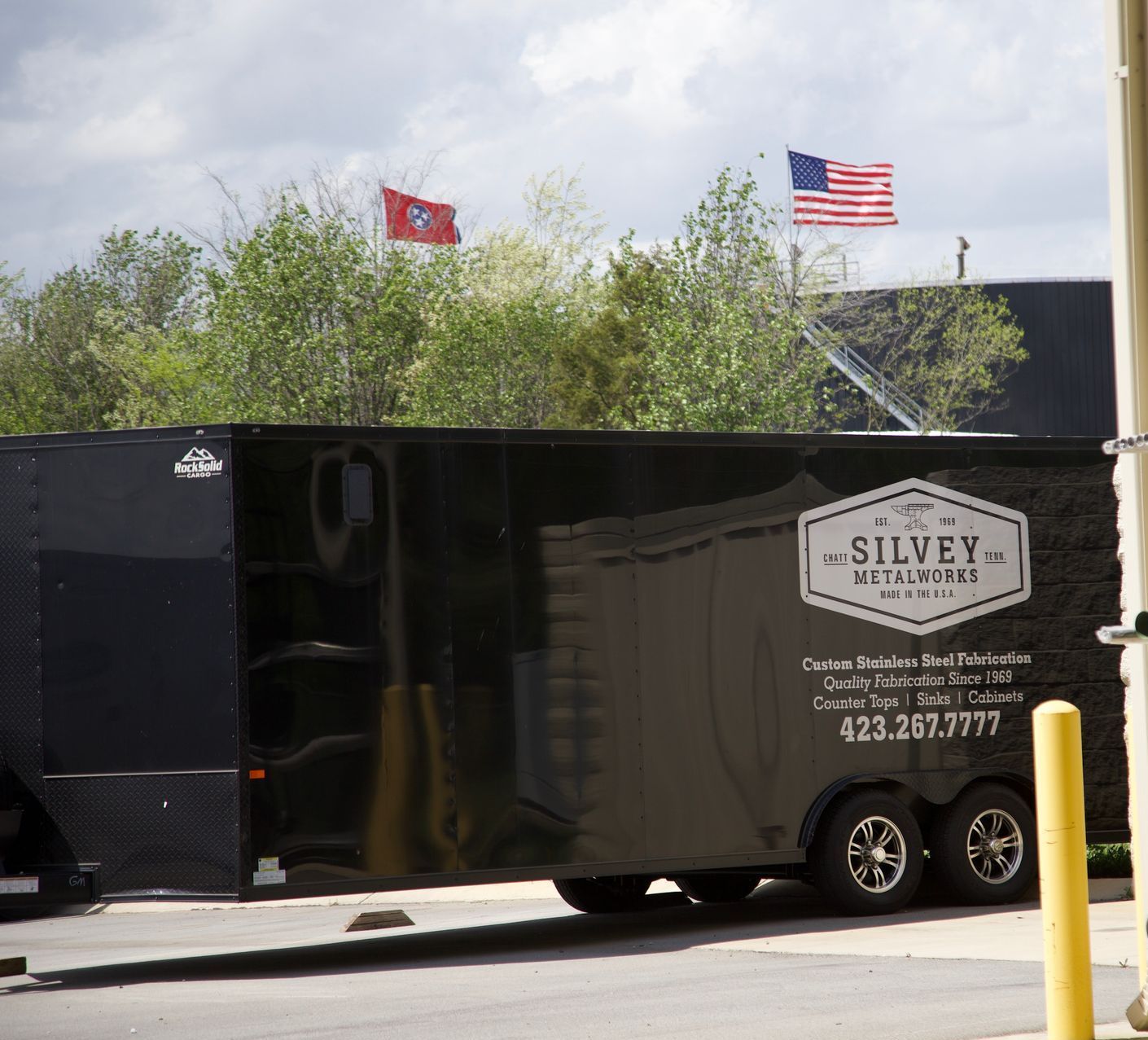 A silver trailer is parked on the side of the road