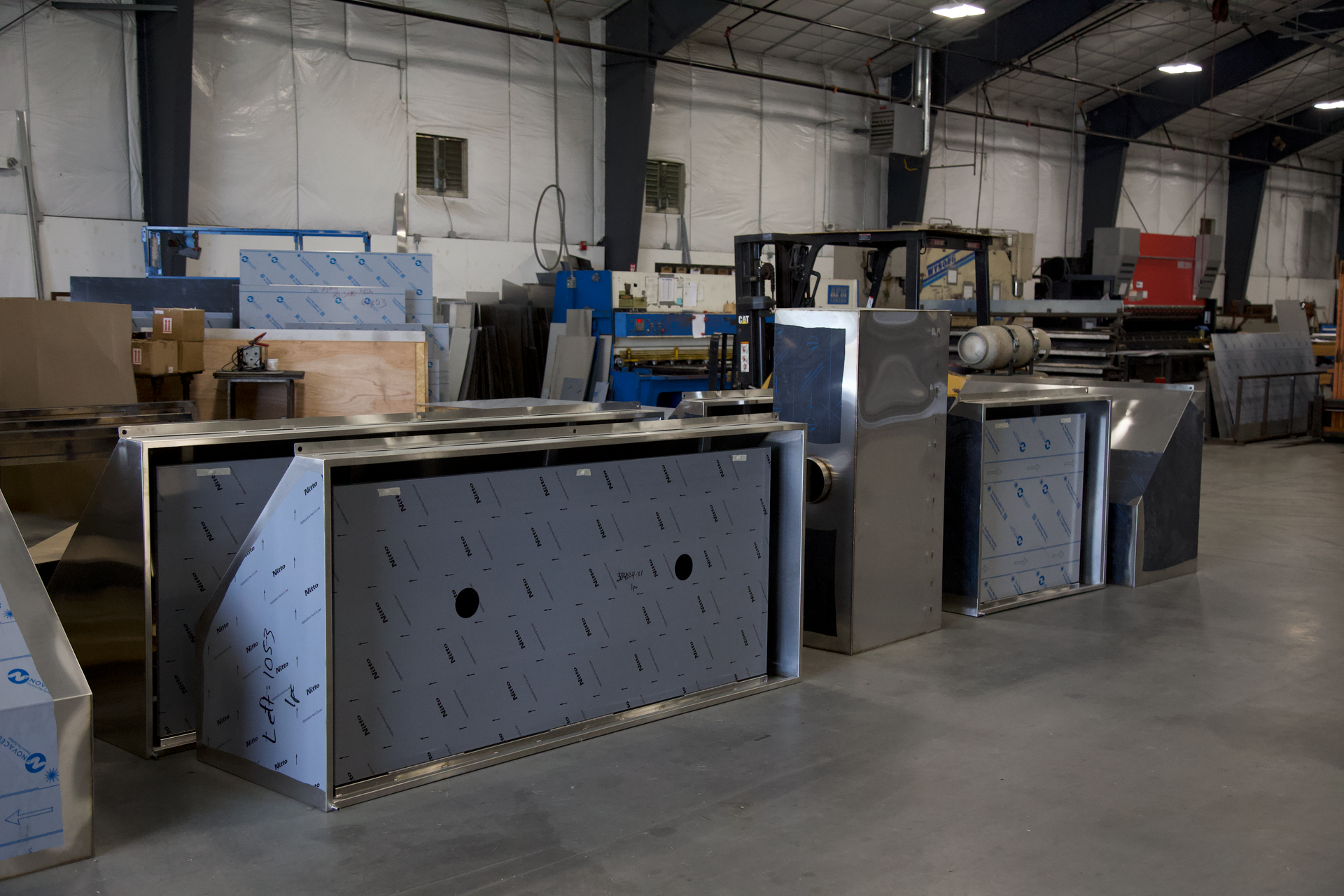 A warehouse filled with lots of stainless steel boxes and machinery.