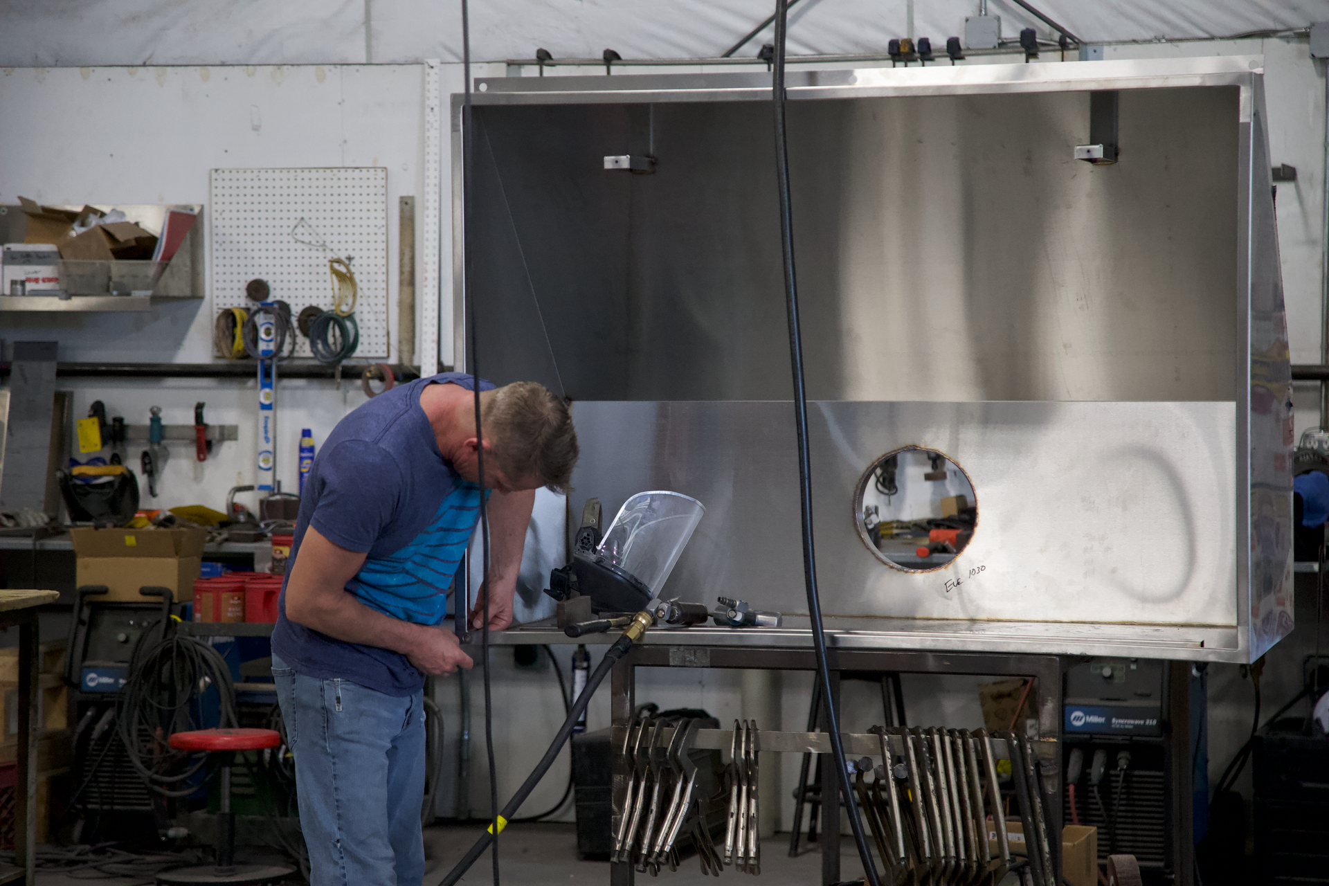 A man is working on a piece of metal in a workshop.