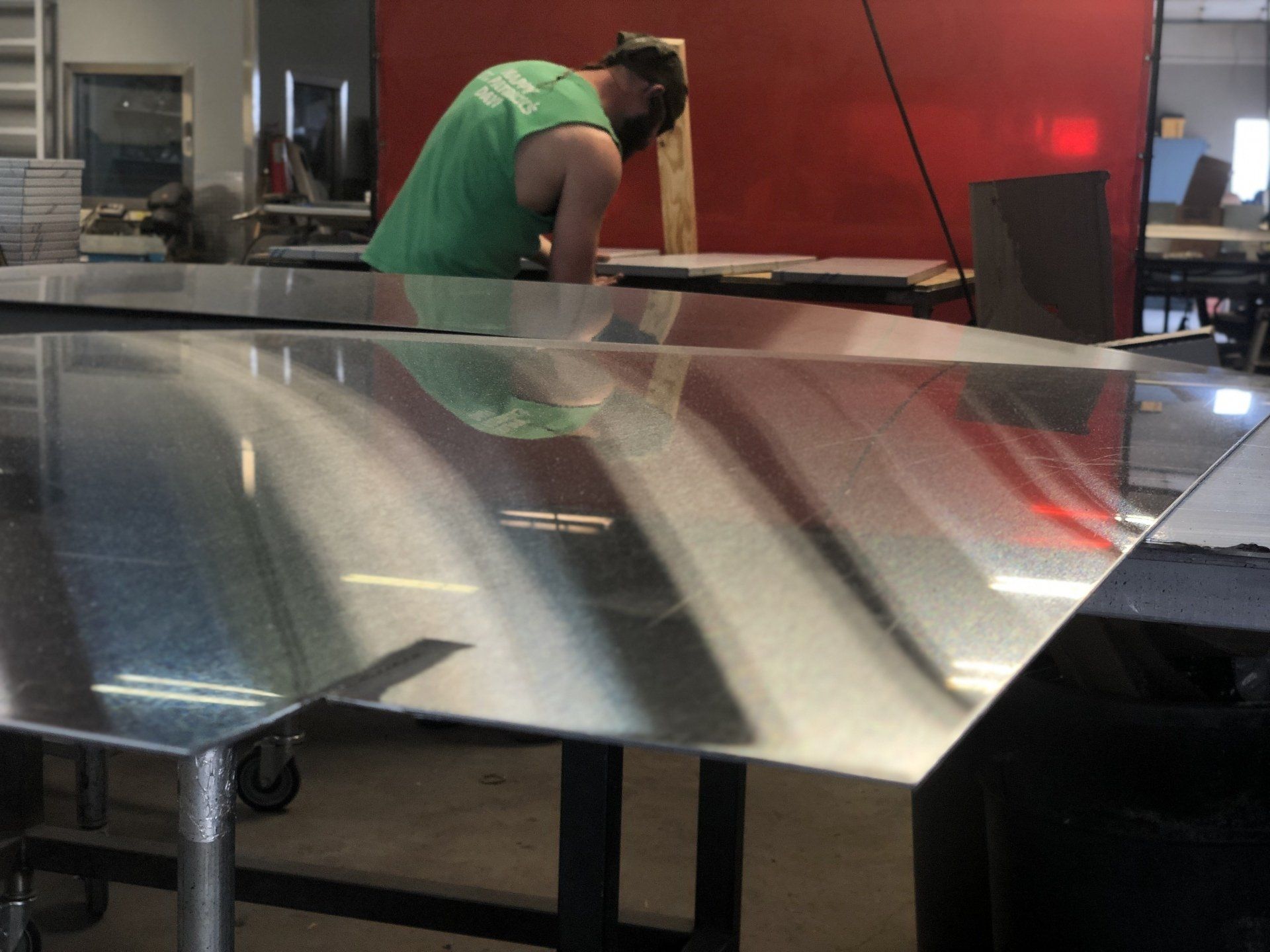 A man in a green shirt is working on a piece of metal
