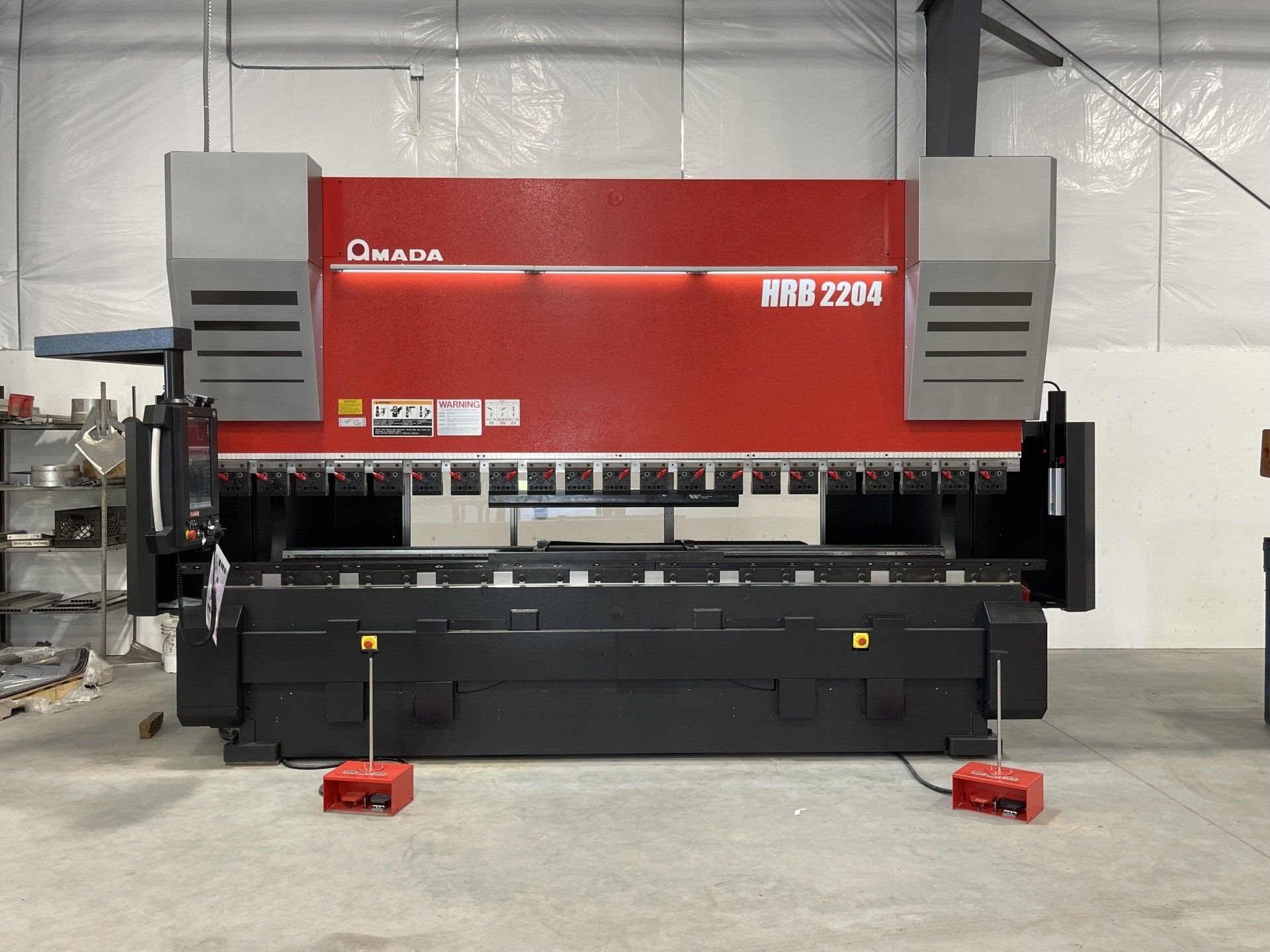 A red and black machine is sitting in a warehouse.