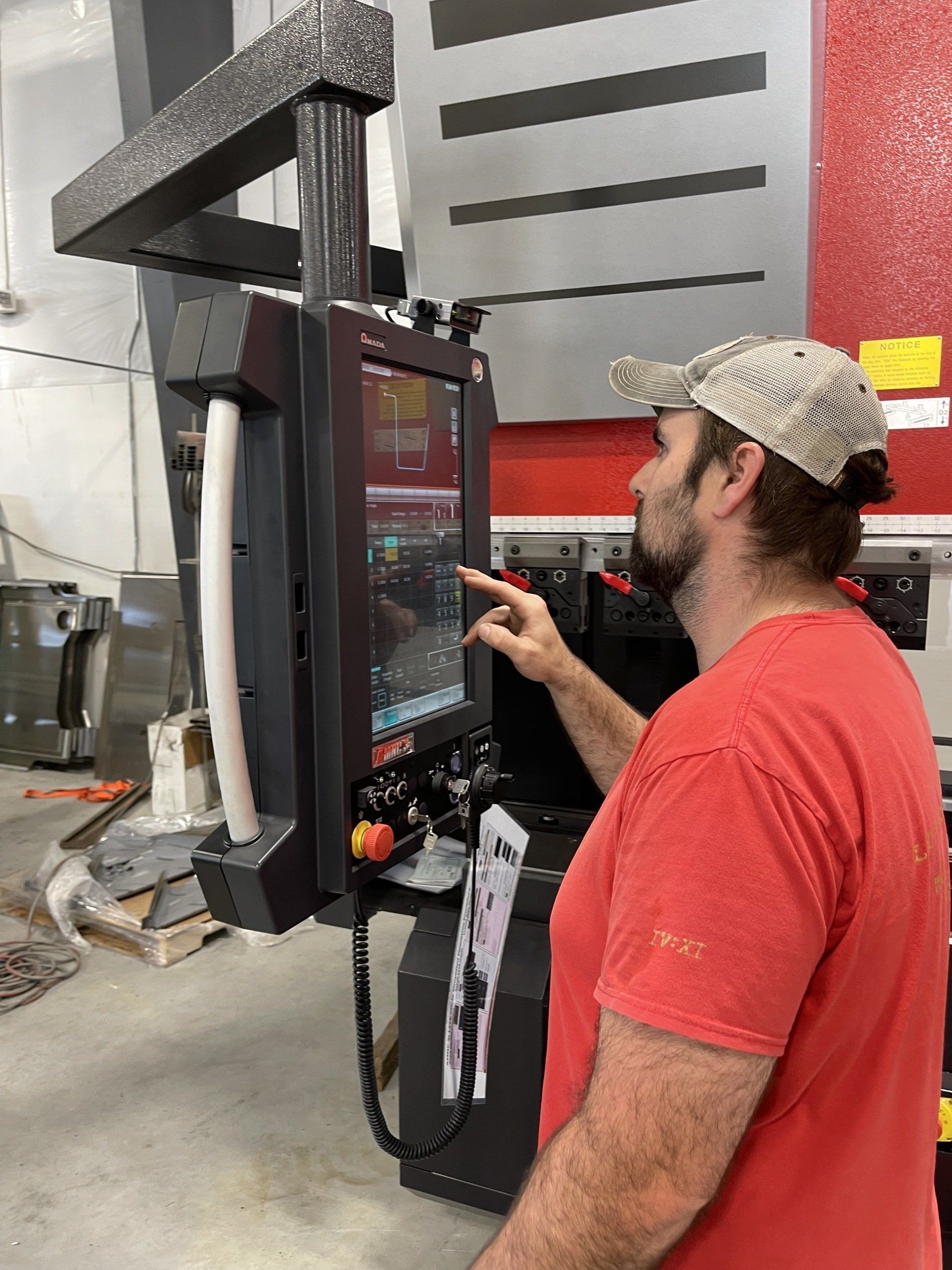 A man is standing in front of a machine and pointing at the screen.
