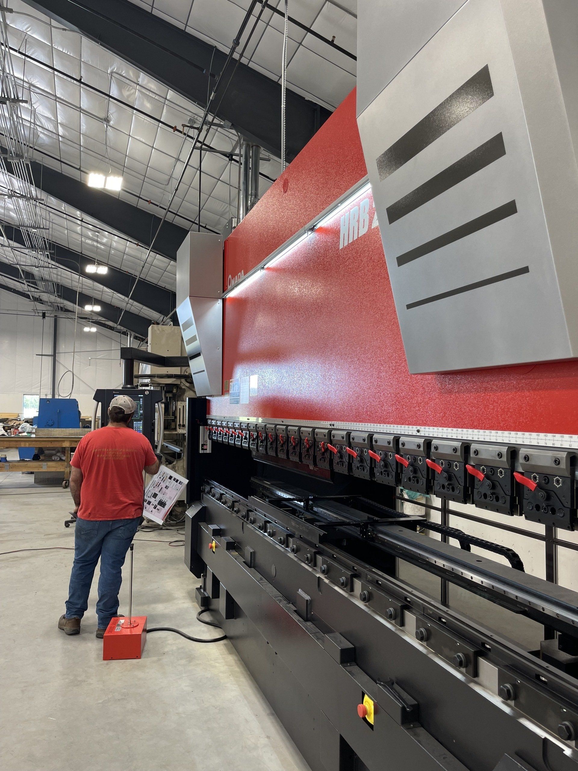 A man in a red shirt is working on a machine in a factory.