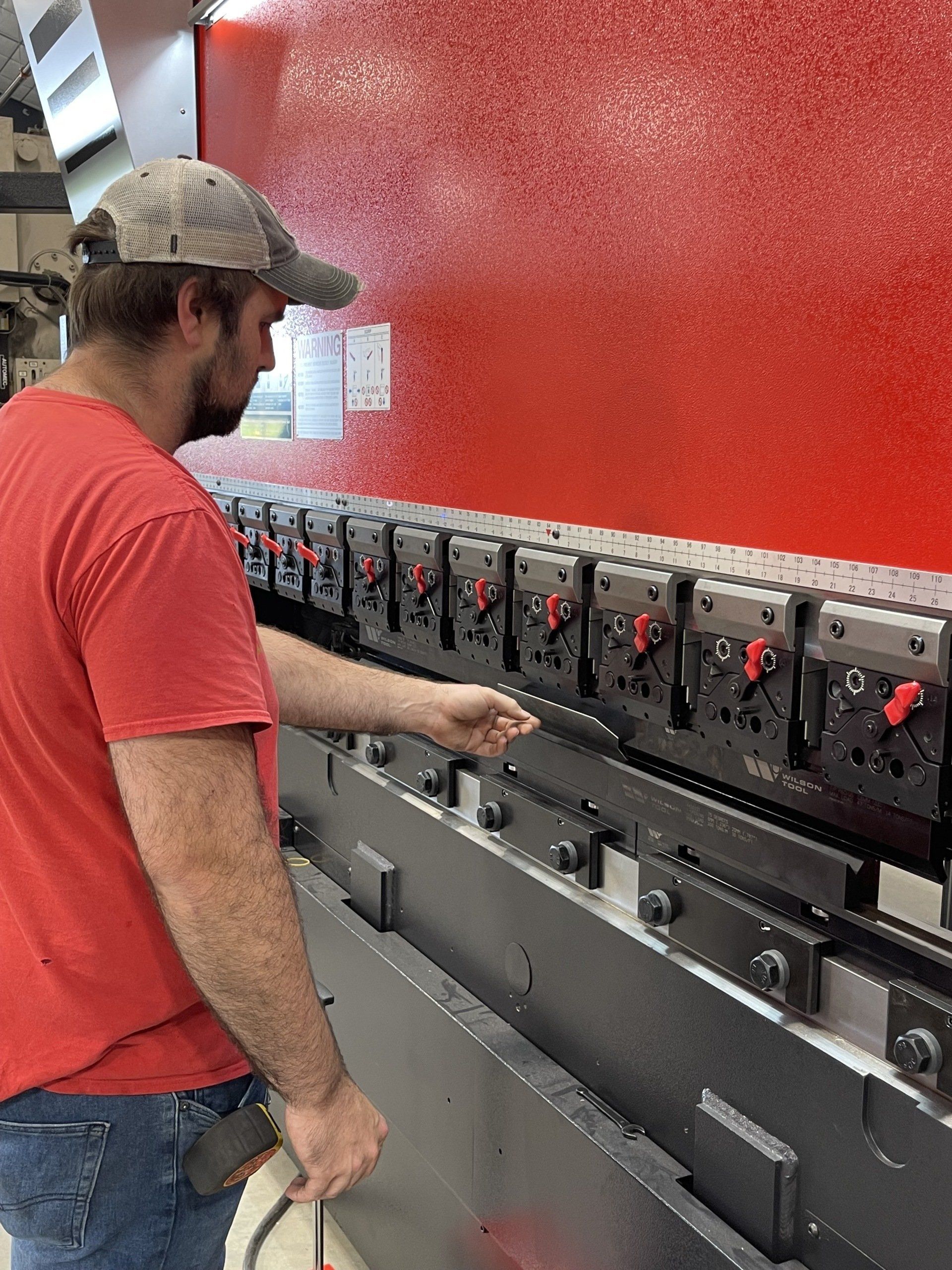 A man in a red shirt is working on a machine.