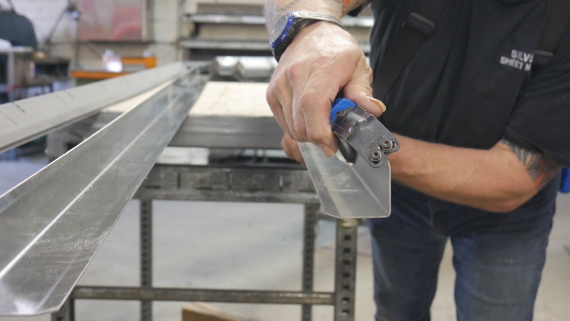 A man is cutting a piece of metal with a pair of scissors.