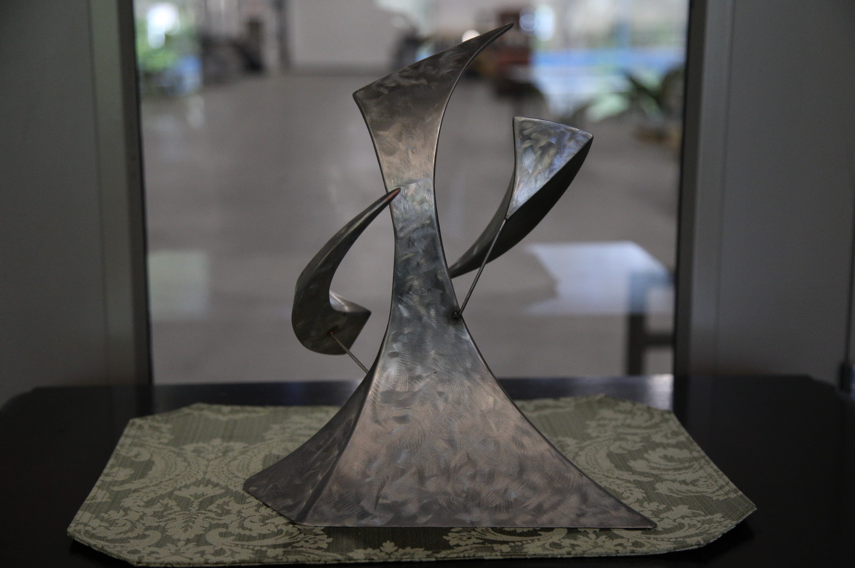 A sculpture is sitting on a table in front of a window.