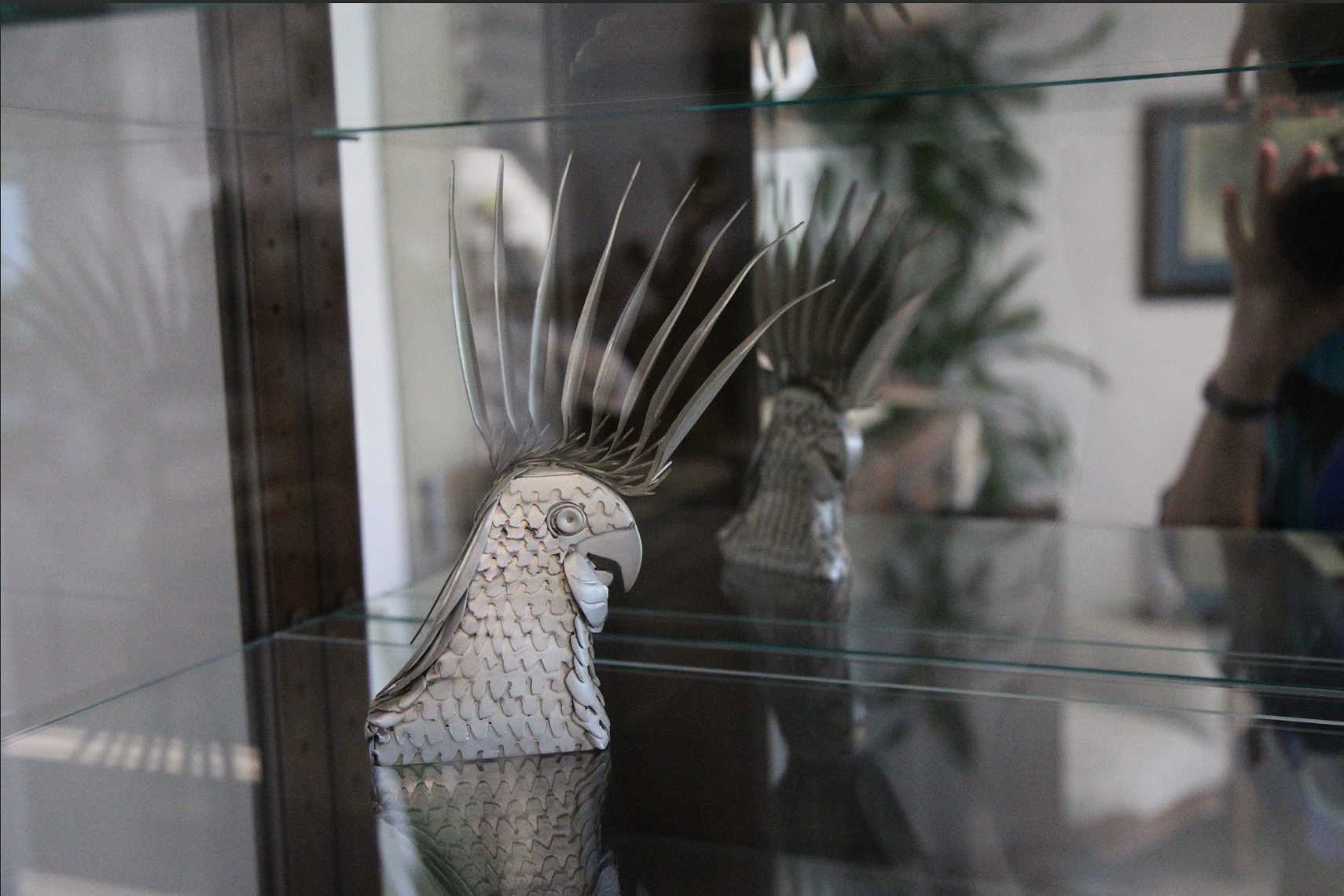 A glass display case with a statue of a bird on it