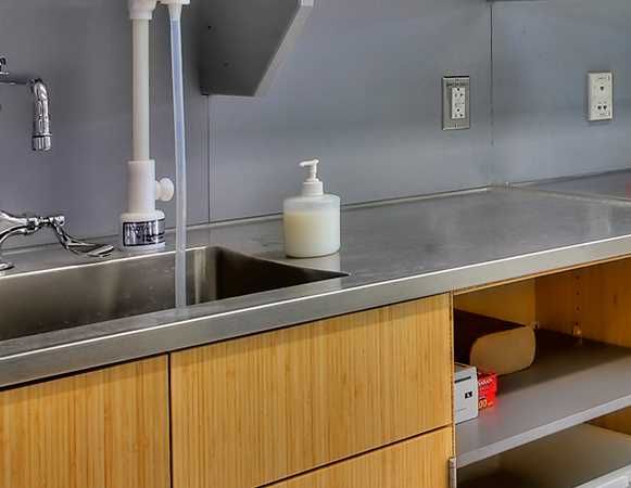 A sink with a soap dispenser on top of it in a kitchen.