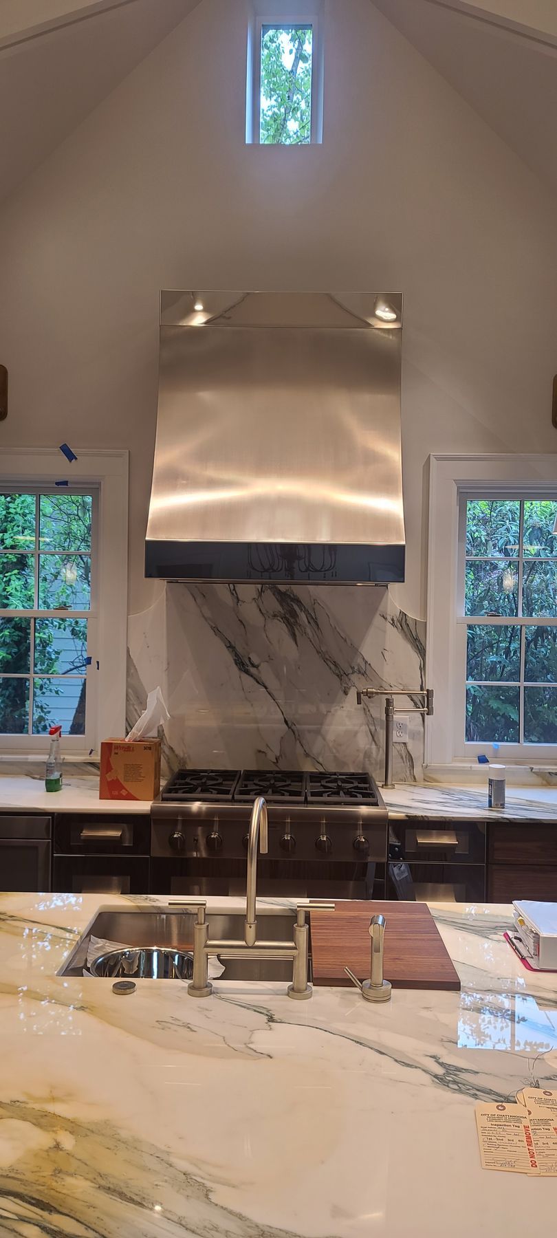 A kitchen with a stove , sink , and stainless steel hood.